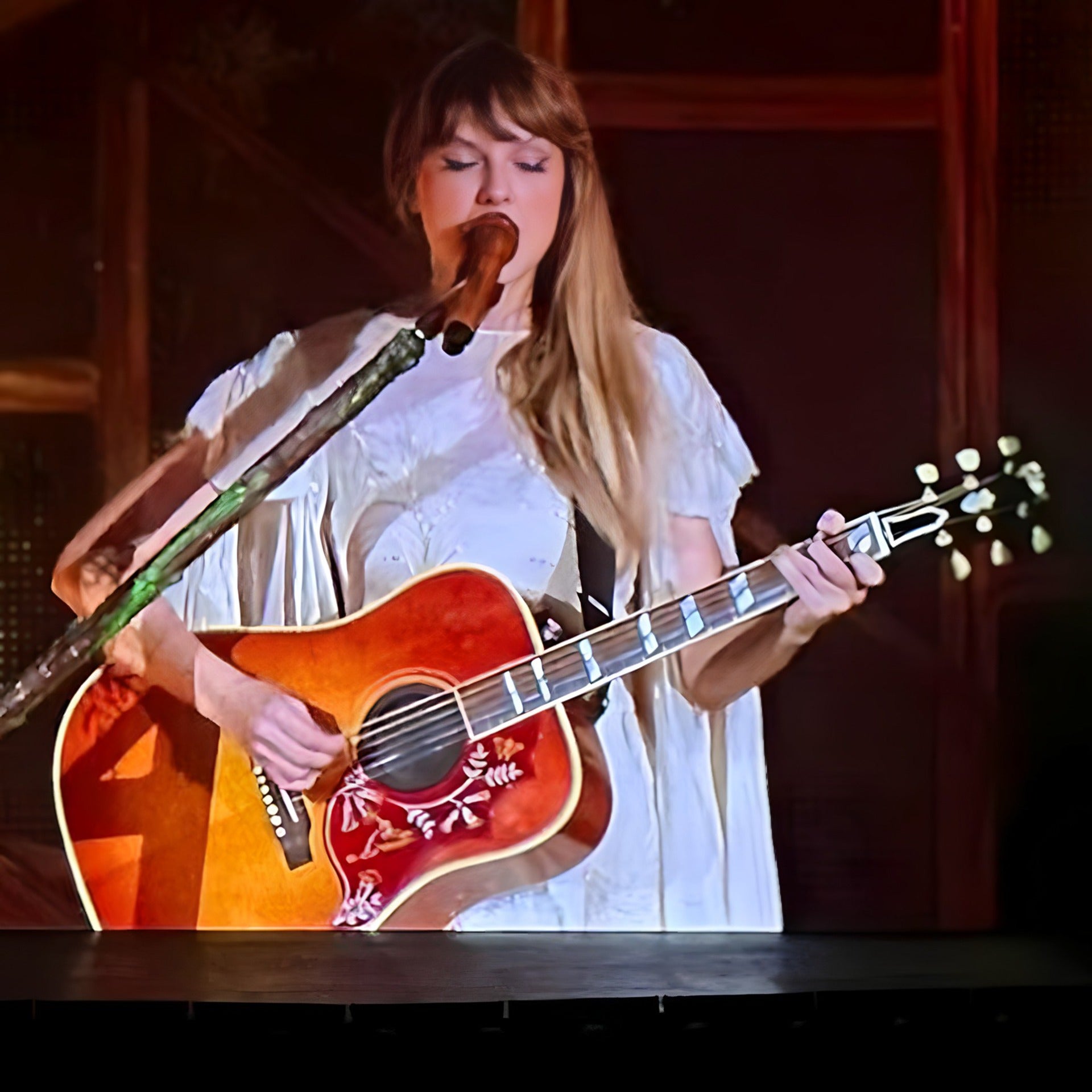 Taylor Swift performing the Folklore set at the Eras Tour while singing with her guitar in hand